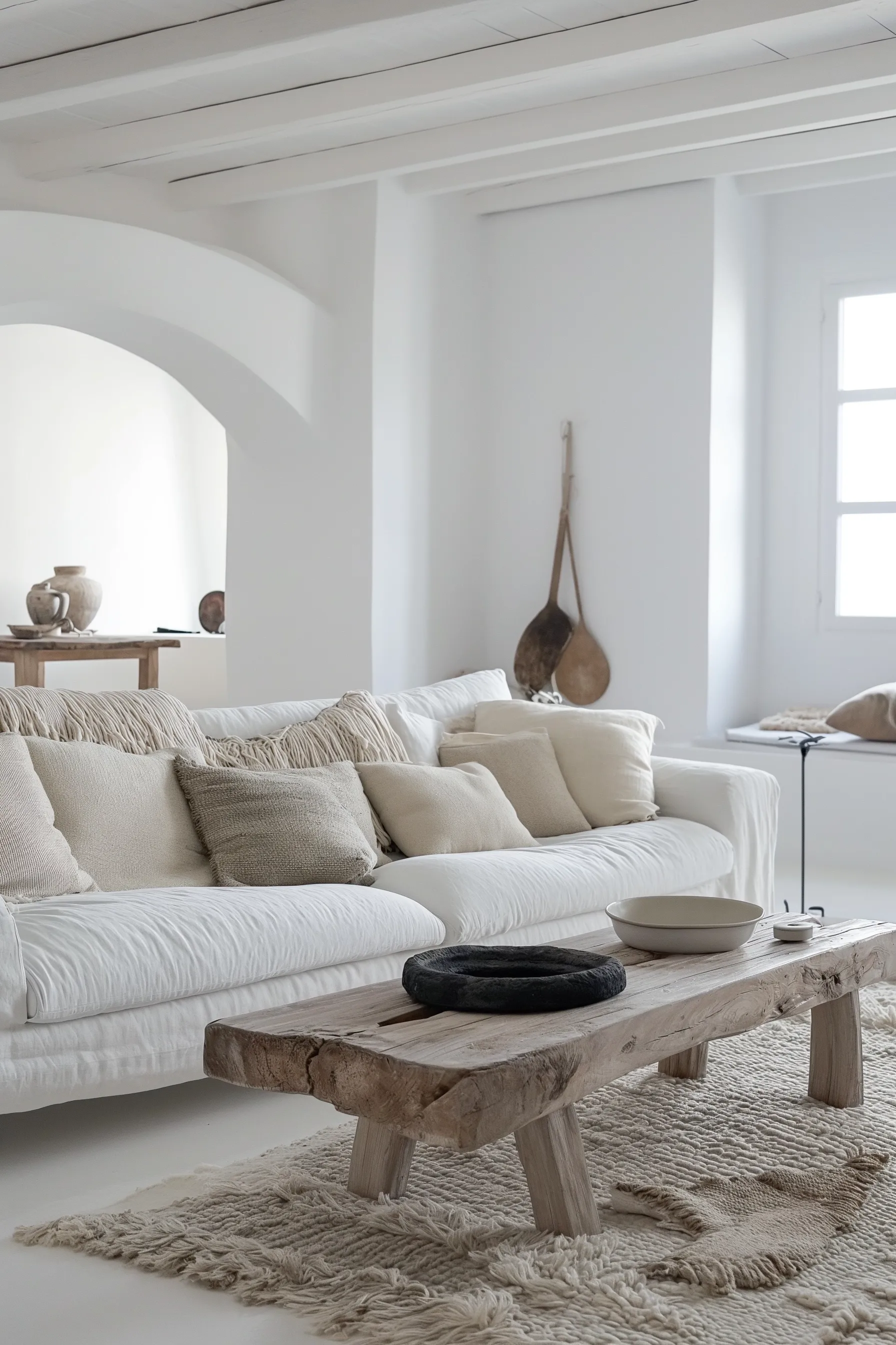 A white living room with a fluffy rug and wooden bench