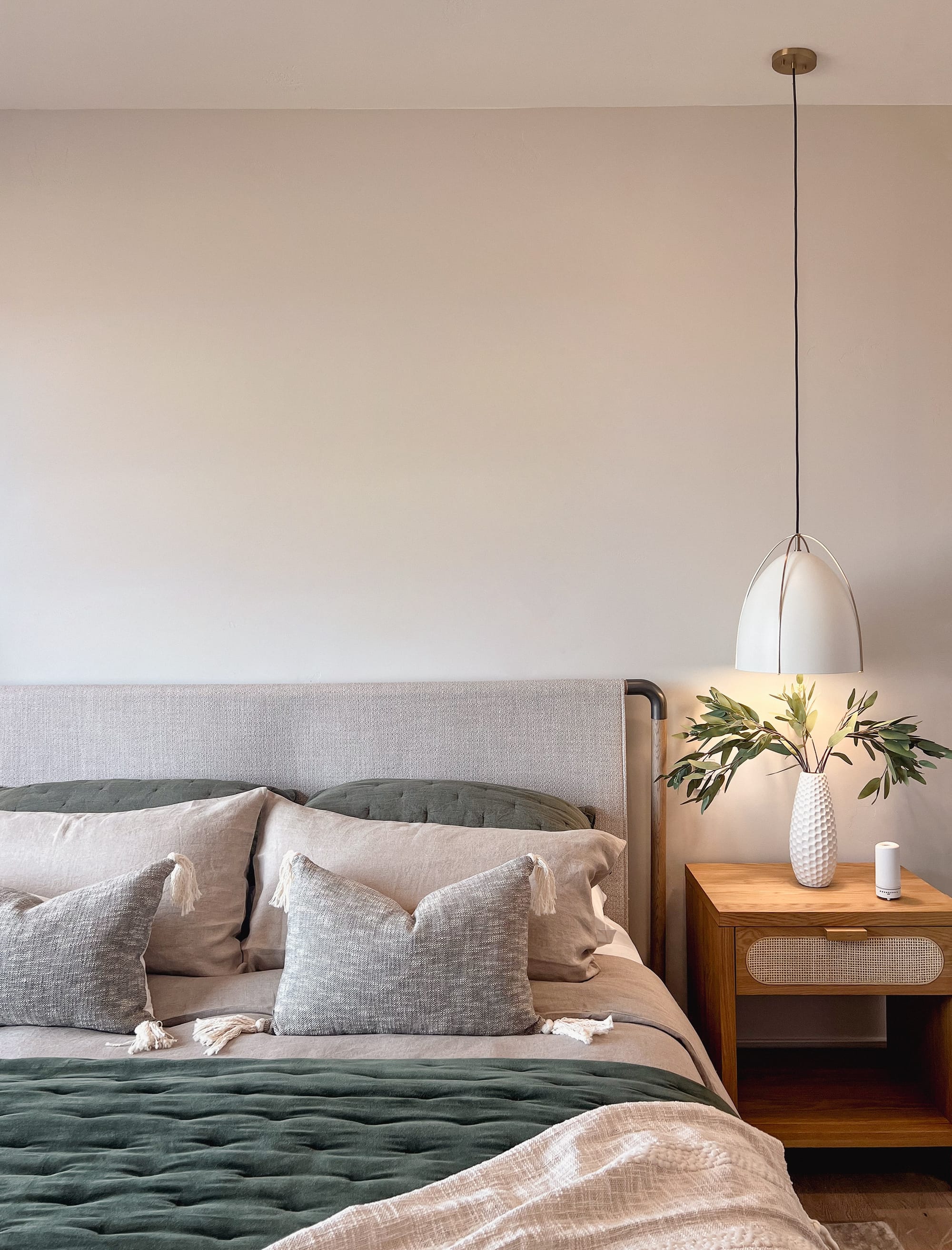 A green and grey bed with a wooden side table.